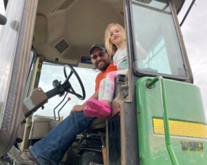 Farmer in tractor with young girl