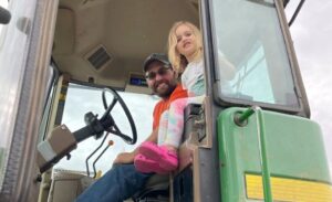 Farmer in tractor with young girl