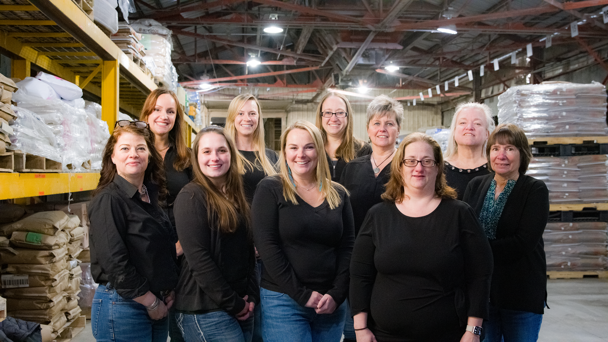 Phoenix office staff Women standing together in black shirts in a production facility posed